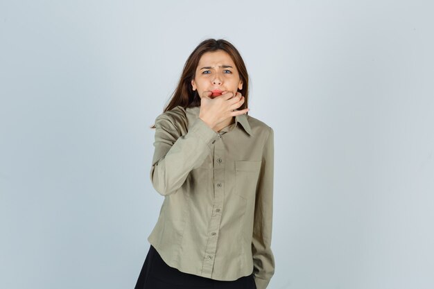 Jolie jeune femme sifflant avec les doigts en chemise, jupe et semblant excitée. vue de face.