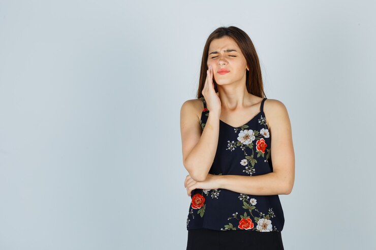 Photo gratuit jolie jeune femme souffrant de terribles maux de dents en chemisier et semblant ennuyée, vue de face.