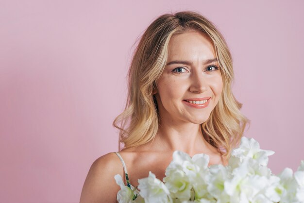 Une jolie jeune femme tenant une fleur blanche fraîche