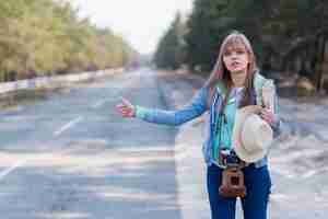 Photo gratuite jolie jeune femme touriste faisant de l'auto-stop le long d'une route