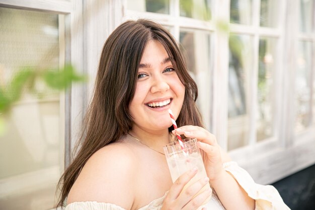 Jolie jeune femme avec un verre de limonade sur la terrasse du café