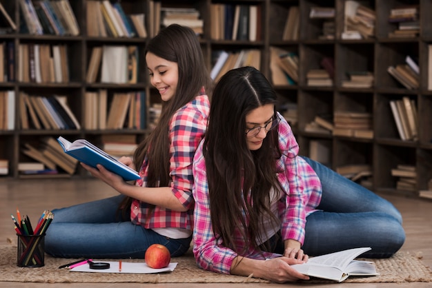 Photo gratuite jolie jeune fille et femme ensemble à la bibliothèque