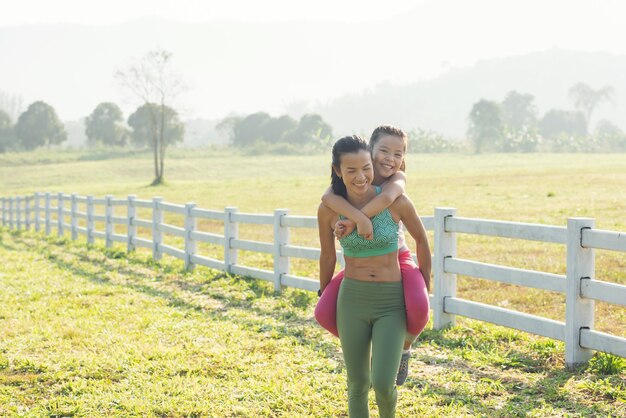 Jolie jeune fille sur un ferroutage avec sa mère qui passe du temps à la campagne. famille heureuse sur le pré en été dans la nature. sports de plein air et fitness, apprentissage de l'exercice pour le développement des enfants.