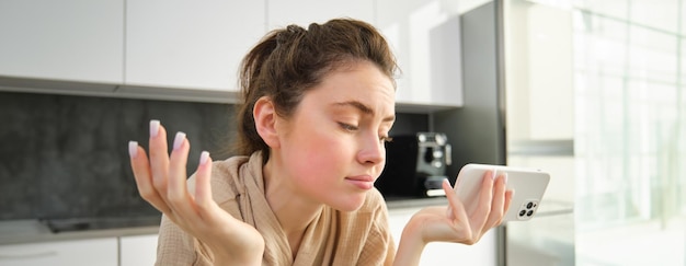 Jolie jeune fille joyeuse cuisinant à la cuisine faisant de la pâte tenant un livre de recettes ayant des idées