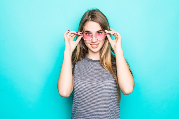 Jolie jeune mannequin en t-shirt de mode, chapeau et lunettes transparentes isolé sur fond vert