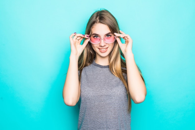 Jolie jeune mannequin en t-shirt de mode, chapeau et lunettes transparentes isolé sur fond vert