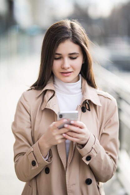 Jolie jeune mannequin texte un message sur son téléphone à l'extérieur