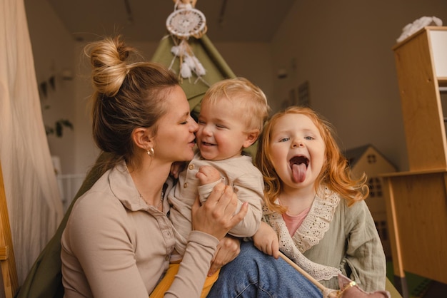 Jolie jeune mère caucasienne fils et fille serrant passer du temps ensemble dans la chambre le week-end Les parents jouent avec le concept d'enfants