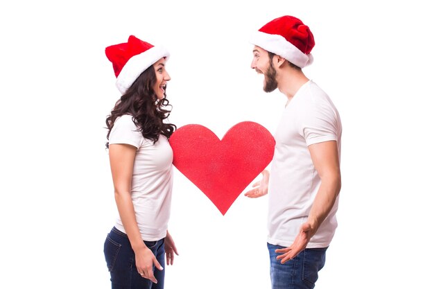 Jolie jeune Santa couple amis homme femme chapeau de Noël tenir grand coeur vide vide isolé sur fond blanc studio. Concept de joyeuses fêtes de célébration de bonne année