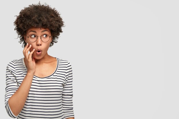 Jolie jolie femme avec une coiffure afro a l'air perplexe