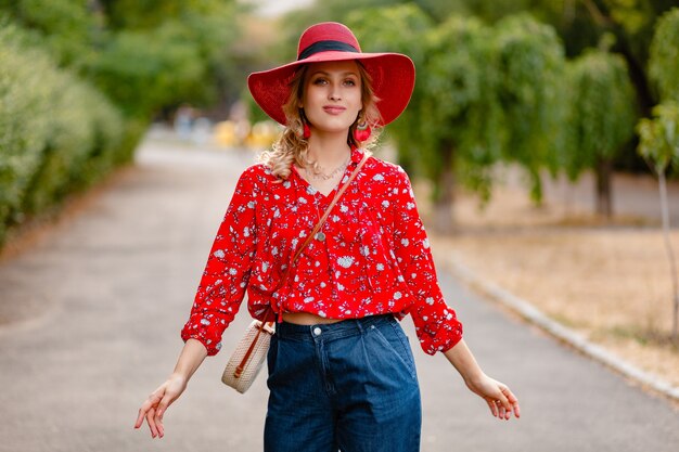 Jolie jolie femme souriante blonde élégante en chapeau rouge de paille et tenue de mode d'été chemisier