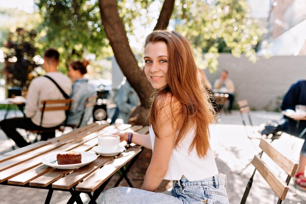 Jolie jolie jeune femme aux longs cheveux brun clair habillé en t-shirt blanc