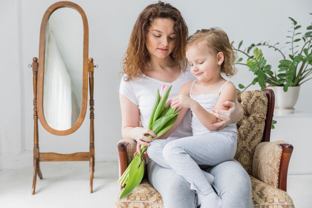 Jolie mère et fille assises sur un fauteuil dans la maison