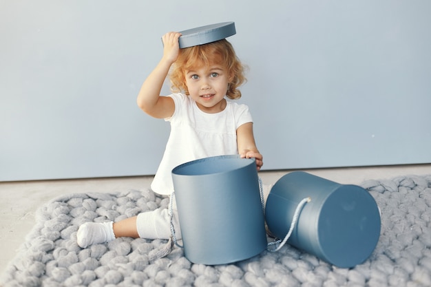 Jolie petite fille assise dans un studio avec boîte de cadeaux