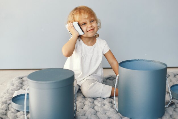 Jolie petite fille assise dans un studio avec boîte de cadeaux