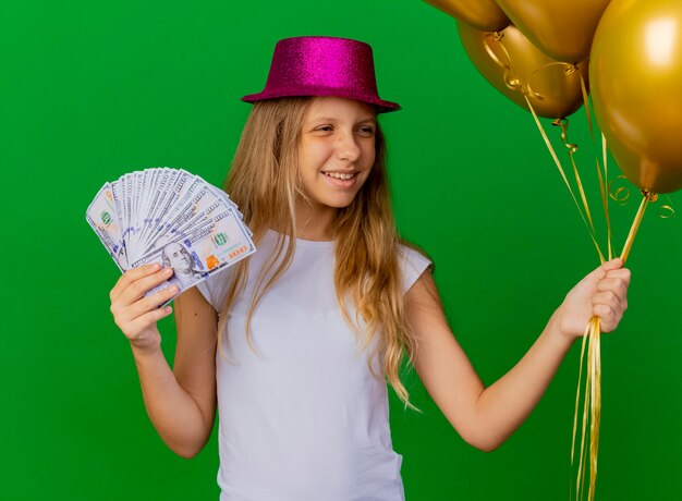 Jolie petite fille au chapeau de vacances tenant de l'argent