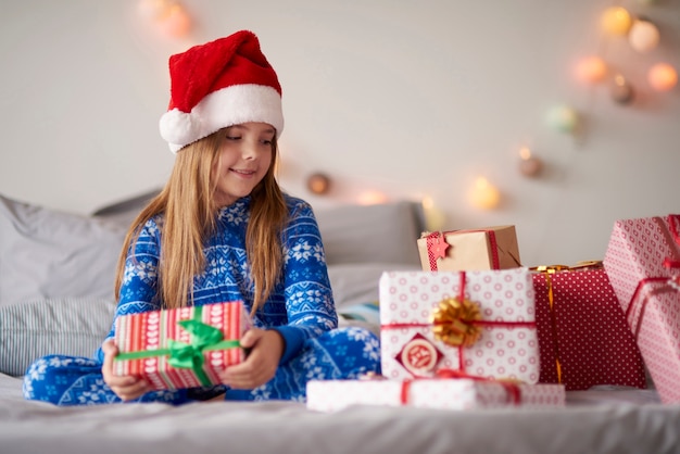 Jolie petite fille au lit avec des cadeaux de Noël