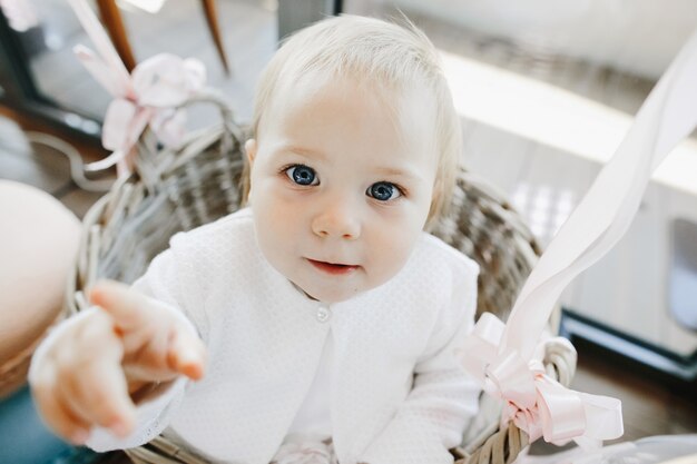 Jolie petite fille aux yeux bleus se trouve dans un panier