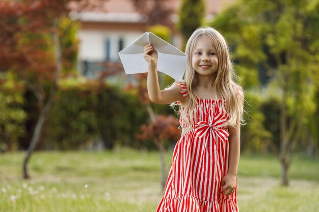 jolie petite fille avec un avion en papier en plein air