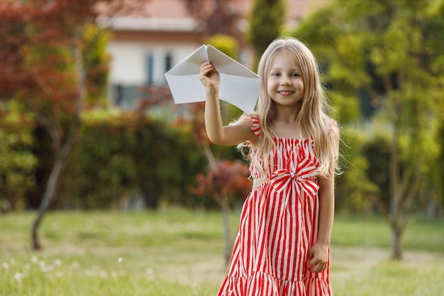 jolie petite fille avec un avion en papier en plein air