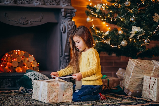 Jolie petite fille avec des cadeaux près du sapin de Noël