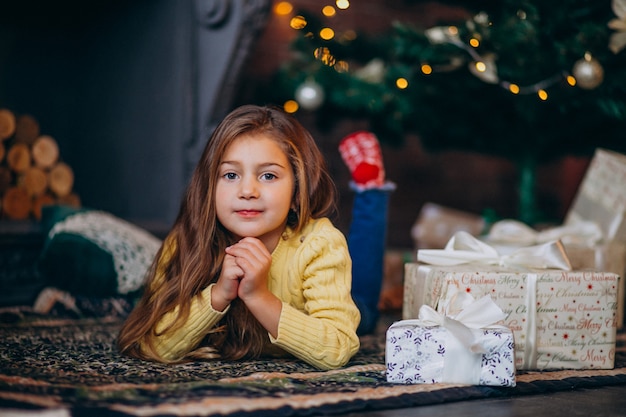 Jolie petite fille avec des cadeaux près du sapin de Noël