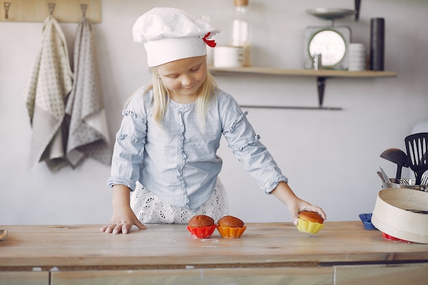 Photo gratuite jolie petite fille dans une cuisine avec cupcake