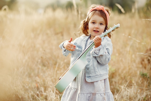 Jolie petite fille dans un parc jouant de la guitare