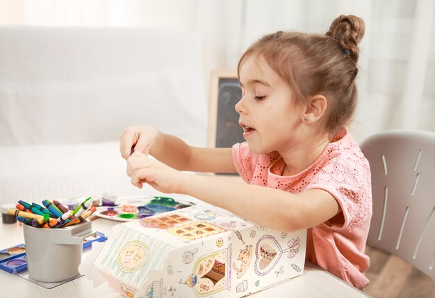 Jolie petite fille dessin avec des crayons à la maison