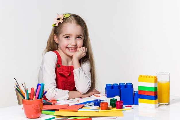 Jolie petite fille dessin avec de la peinture et un pinceau à la maison