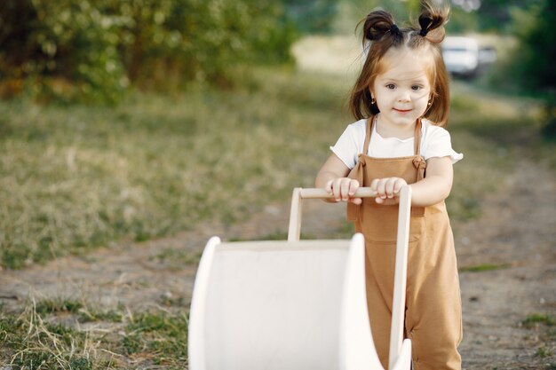 Jolie petite fille jouant dans un parc avec chariot blanc