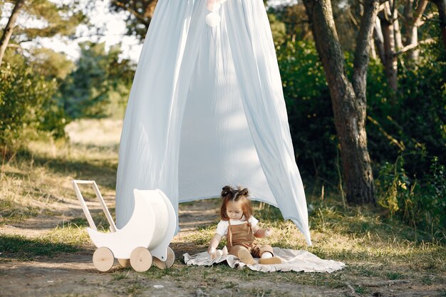 Jolie petite fille jouant dans un parc avec chariot blanc