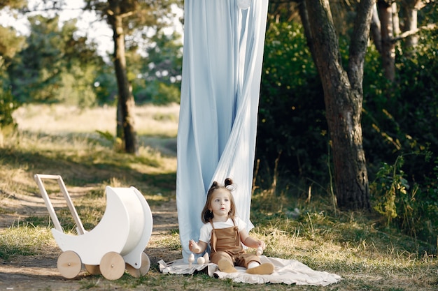 Jolie petite fille jouant dans un parc avec chariot blanc