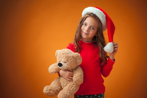 La jolie petite fille joyeuse avec ours en peluche sur fond orange