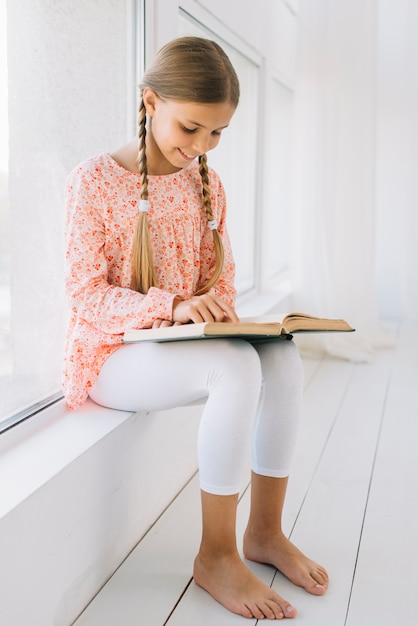 Photo gratuite jolie petite fille lisant un livre