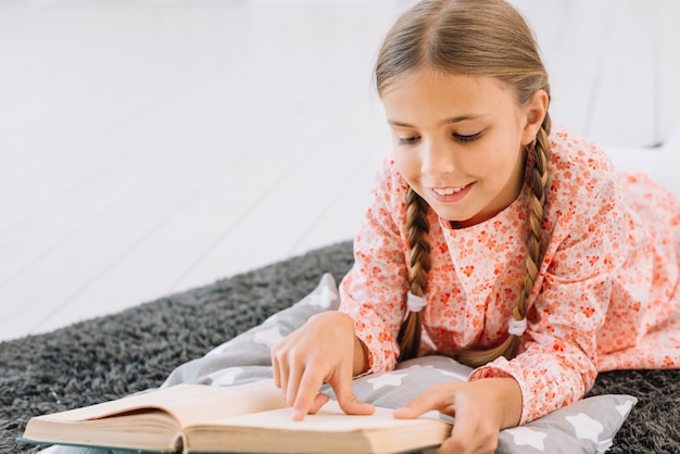 Photo gratuite jolie petite fille lisant un livre