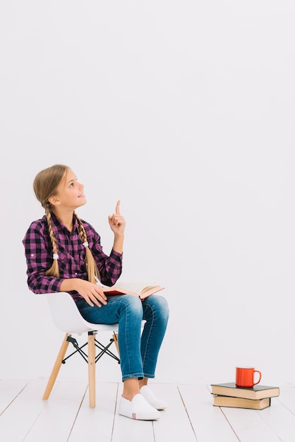 Jolie petite fille avec un livre pointant vers le haut