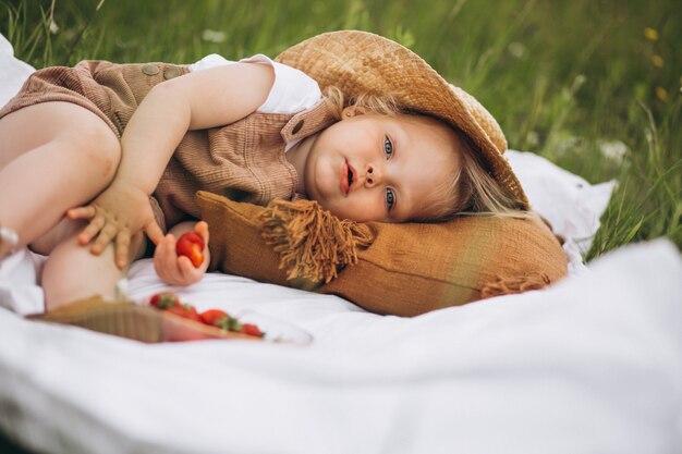 Jolie petite fille en pique-nique dans le parc, manger des fraises