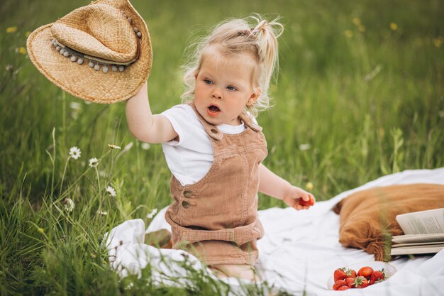 Jolie petite fille en pique-nique dans le parc, manger des fraises