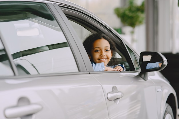 Jolie petite fille à la recherche de la voiture. Enfant dans un salon de voiture.