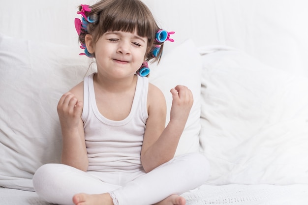 Jolie petite fille souriante en position couchée dans un lit blanc confortable