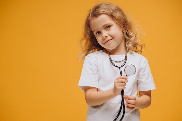 Jolie petite fille avec stéthoscope isolée en studio