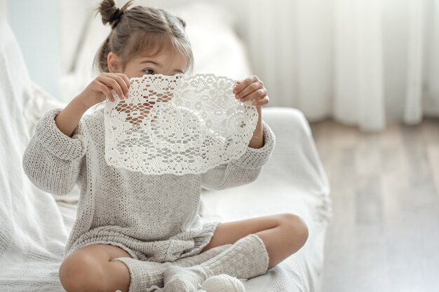 Jolie petite fille tenant une serviette ajourée à la main dans ses mains.