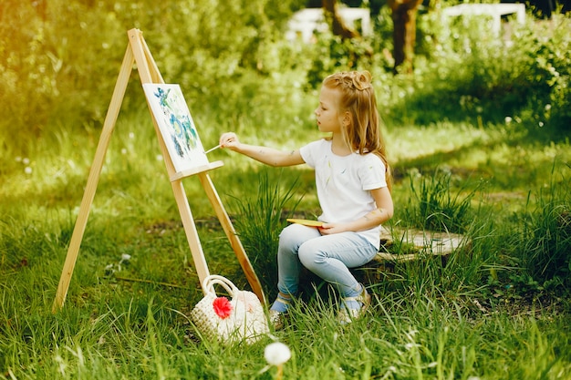 Jolie petite fille en train de peindre dans un parc