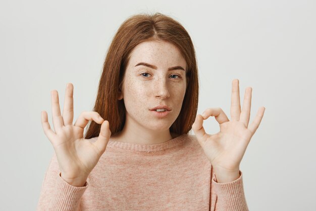 Une jolie rousse confiante montre un geste correct, n'assure aucun problème, tout va bien