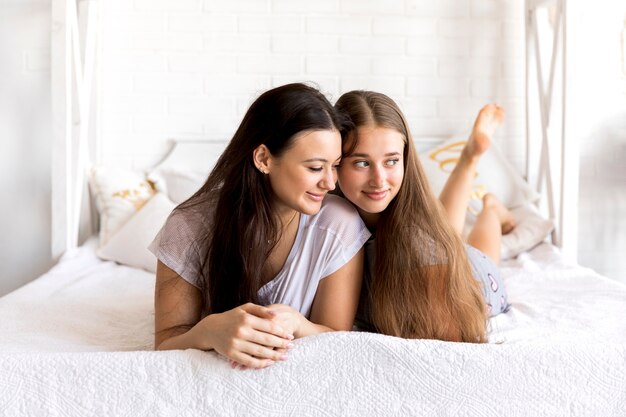 Jolies femmes qui cherchent loin sur le lit