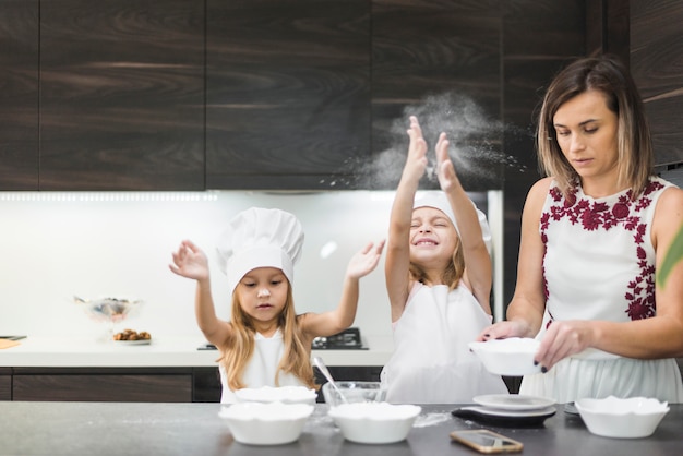 Photo gratuite jolies filles appréciant dans la cuisine pendant que la mère prépare la nourriture