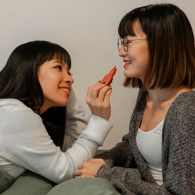 Jolies filles asiatiques essayant des produits de maquillage