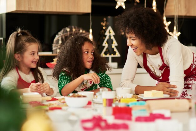 Jolies filles faisant des biscuits avec l'aide de leur maman