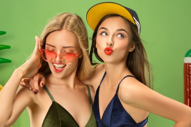 Jolies filles en maillot de bain posant au studio. Portrait d'été adolescents caucasiens sur fond vert.